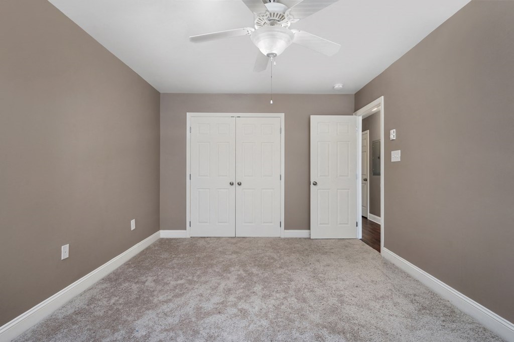 a empty room with two white doors and a ceiling fan