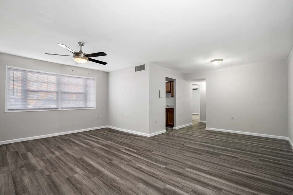 an empty living room with a ceiling fan and a window