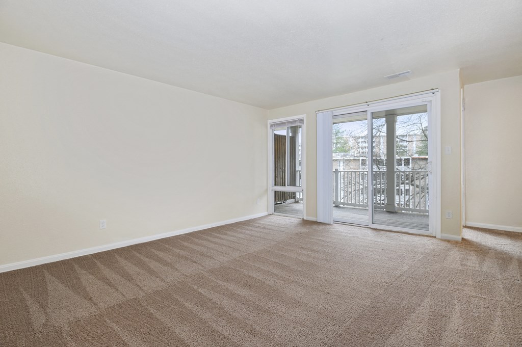 an empty living room with a sliding glass door to a balcony