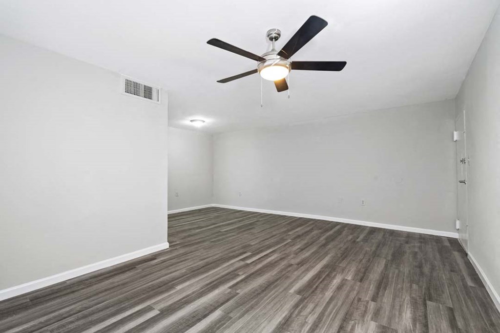 an empty living room with a ceiling fan