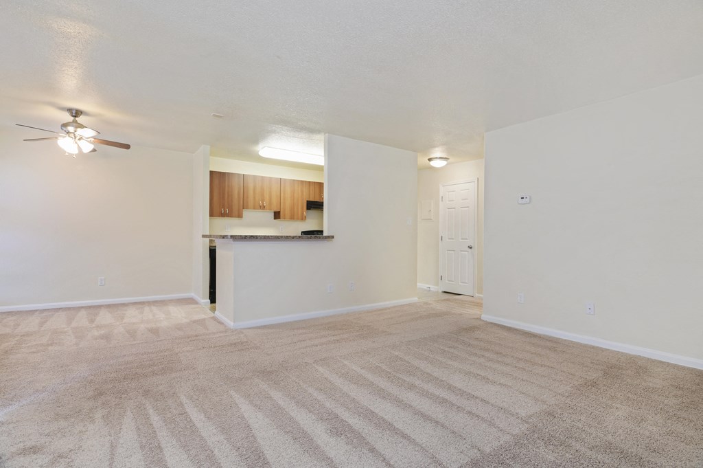 an empty living room and kitchen with a ceiling fan