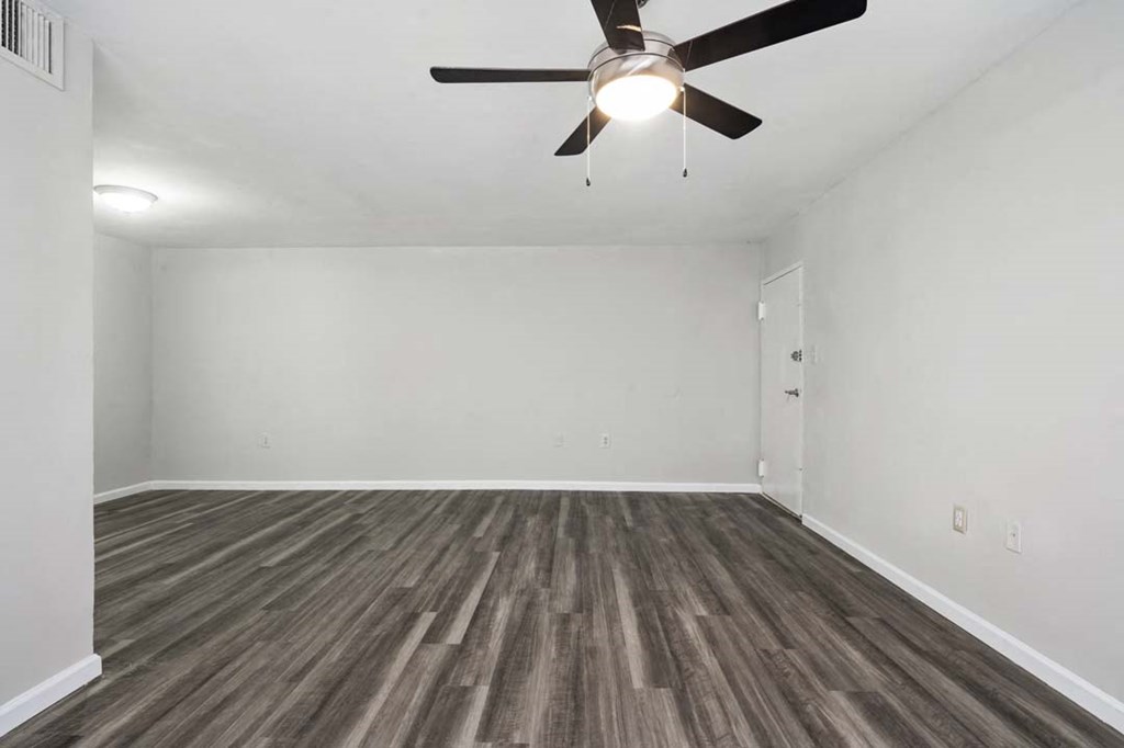 an empty living room with a ceiling fan