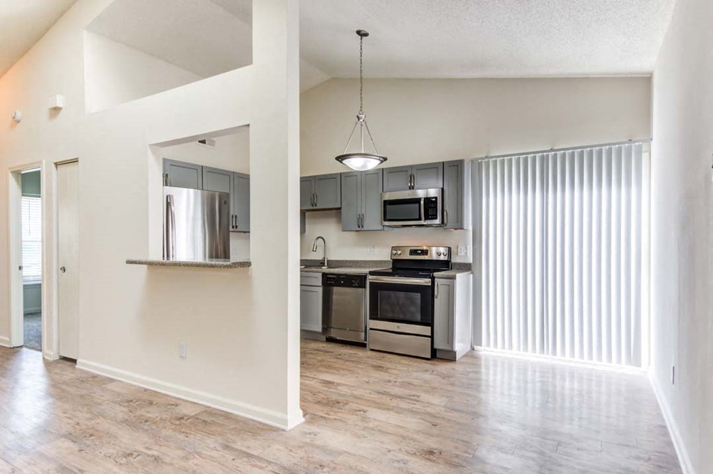 an empty kitchen with stainless steel appliances and a window
