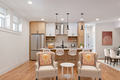 A kitchen with a refrigerator, a sink, and a dining table with chairs.