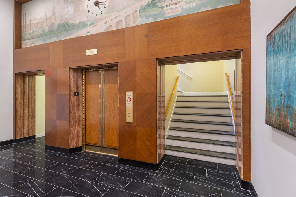 a lobby with elevators and a staircase and a painting on the wall