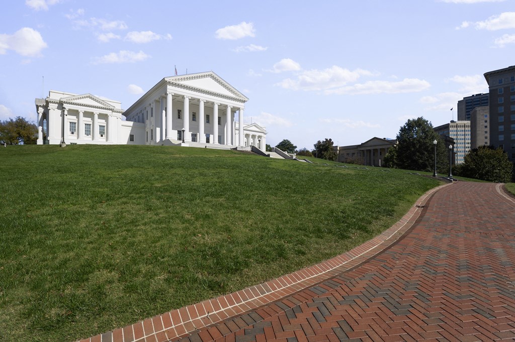 a large white building with columns on top of a grassy hill
