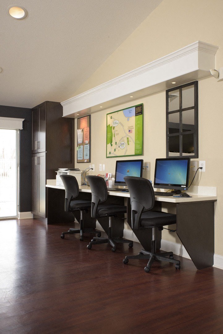 an office with a desk with computers and chairs