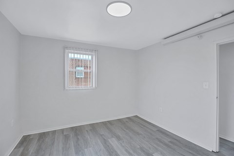 A room with a window and a wooden floor.