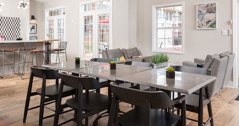 a communal table and chairs in a living room with a kitchen