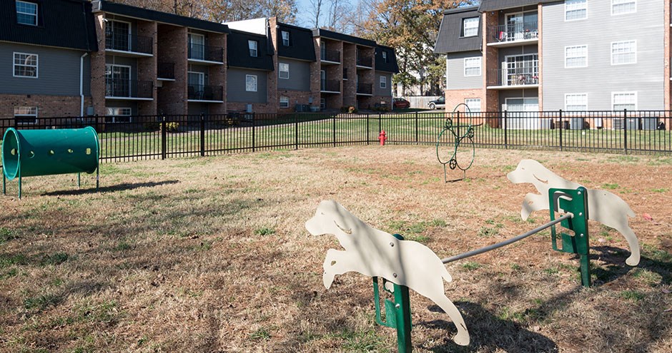 two rocking horses in a park in front of apartment buildings