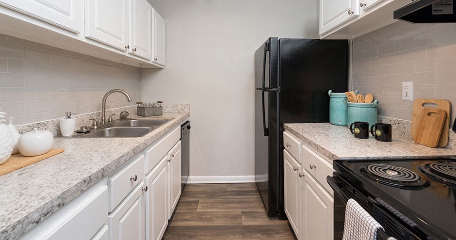 a kitchen with white cabinets and a black refrigerator