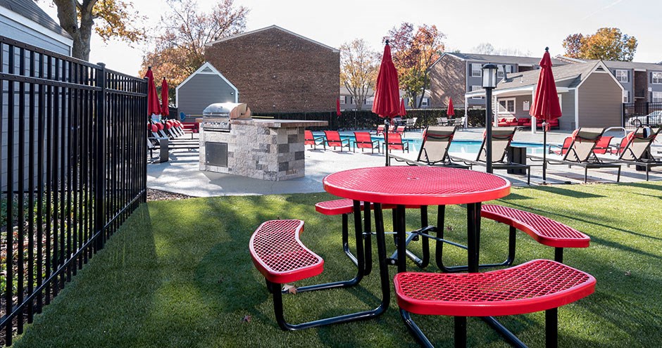 a patio with red tables and chairs and a fire pit