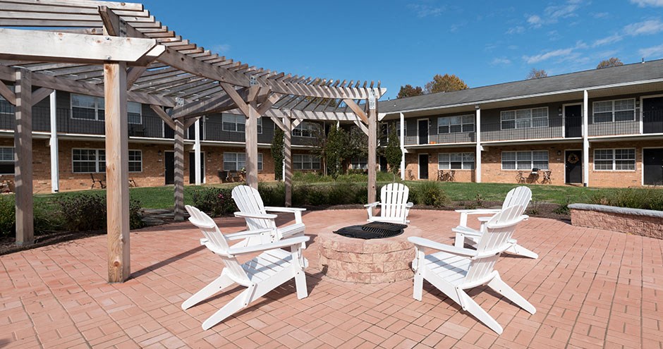 an outdoor patio with rocking chairs and a fire pit