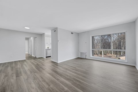 A spacious room with wooden flooring and a large window.