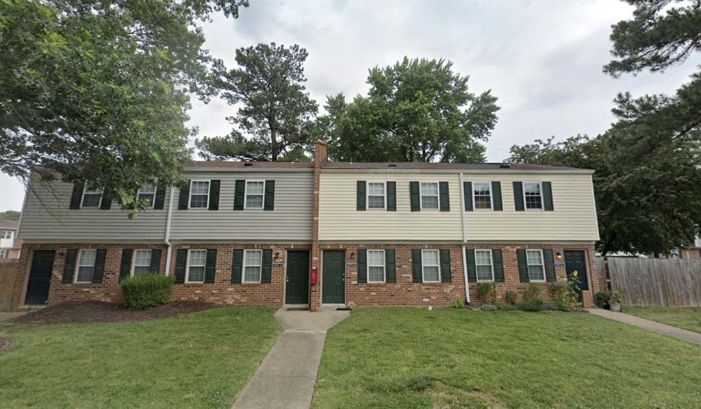 a white house with a green lawn and trees