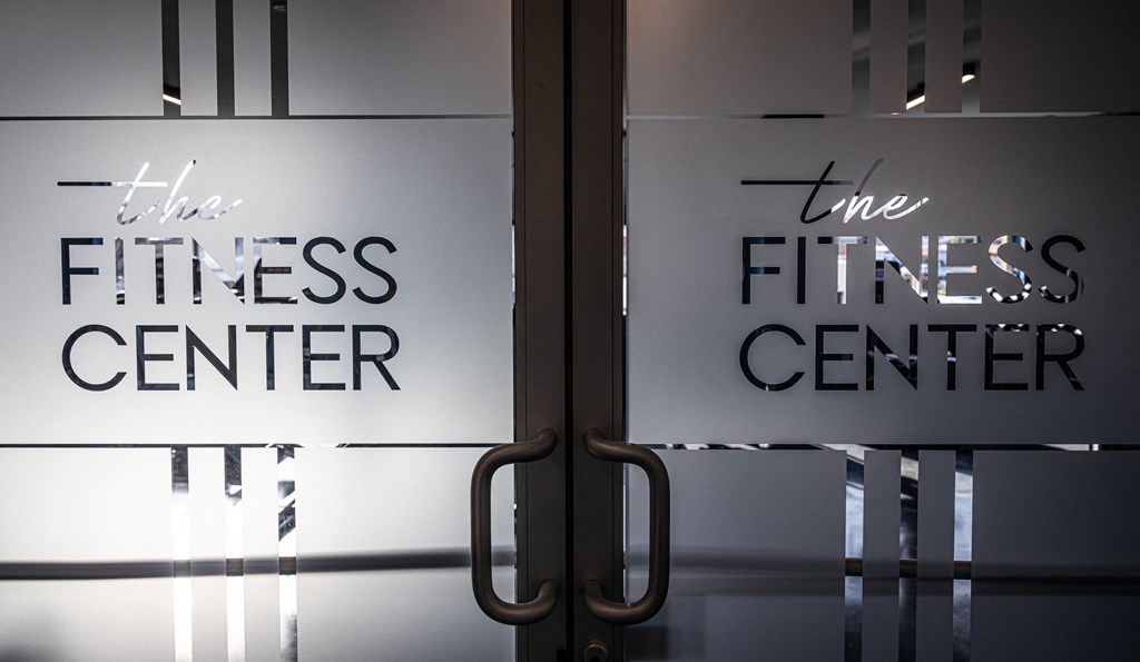 a sign for the fitness center is seen through a glass door