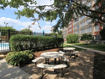 a patio with tables and benches next to a swimming pool