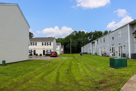 a row of houses on a grassy lot with a blue sky in the background