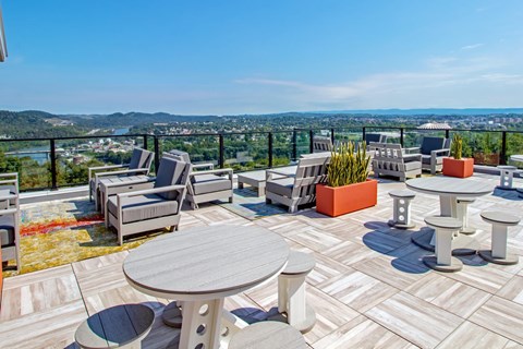 a rooftop deck with tables and chairs overlooking the city