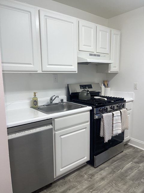 A kitchen with white cabinets and a black stove top oven.