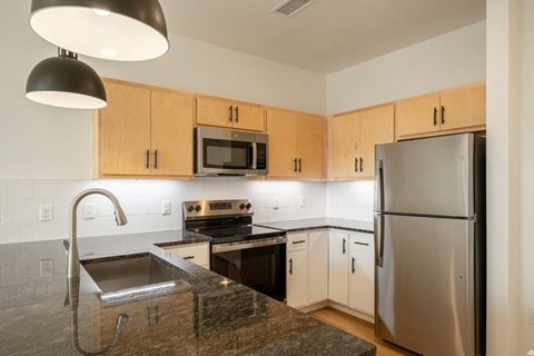A kitchen with a stainless steel refrigerator and a granite countertop.