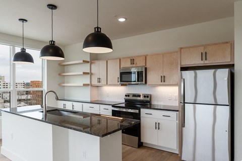 A modern kitchen with black countertops and white cabinets.