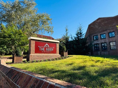 a brick building with a sign for the abbey on a lawn