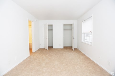 A white room with carpeted floor and two doors.