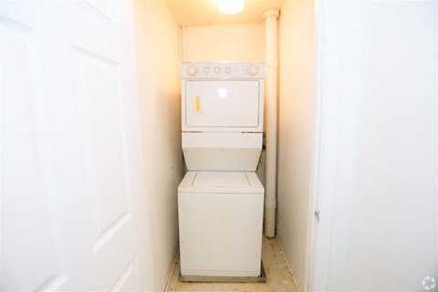 A white washing machine in a small white room.