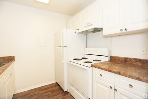 A kitchen with a white refrigerator, stove, and cabinets.