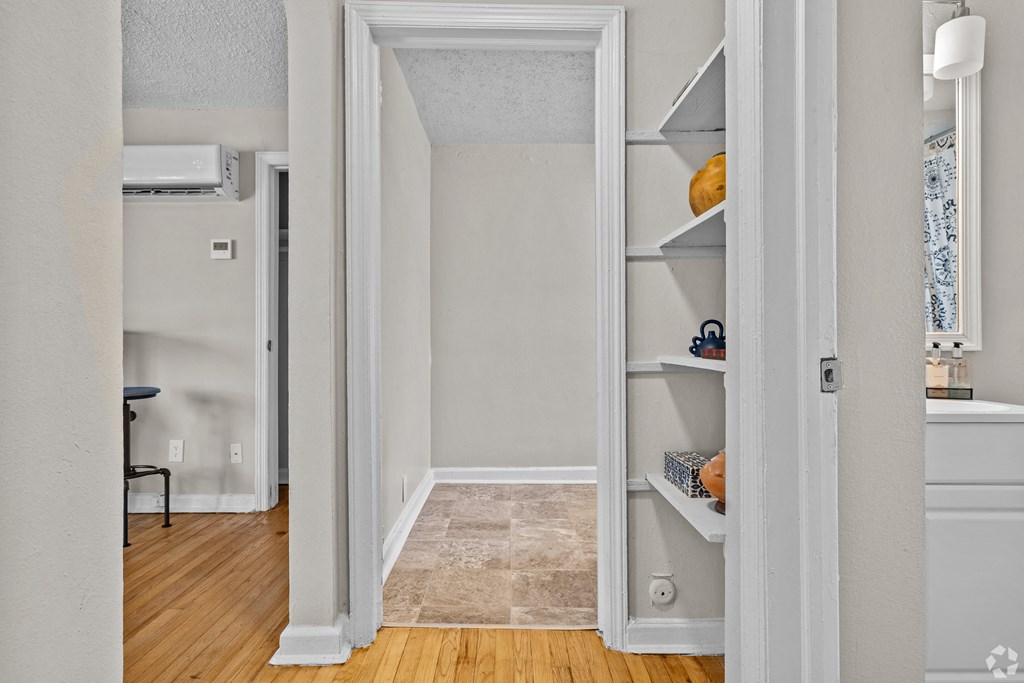 a room with an open closet and a hallway with a hard wood floor