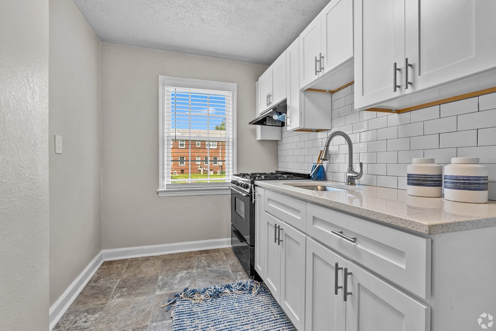 an empty kitchen with white cabinets and a window