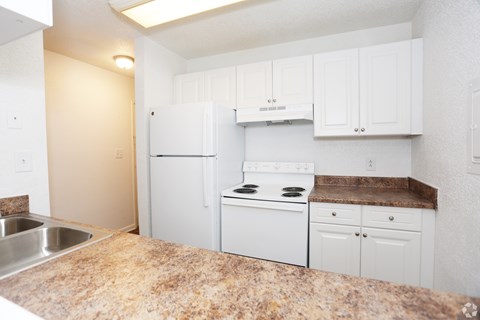A kitchen with white appliances and cabinets.
