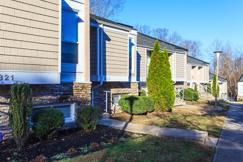 a building with blue shutters and a sidewalk in front of it