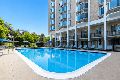 A large swimming pool in front of a multi-story apartment building.