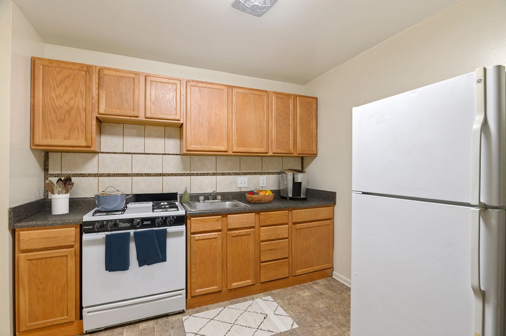 a kitchen with white appliances and wooden cabinets and a refrigerator