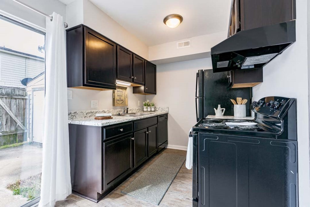 a kitchen with black counters and a stove and a window