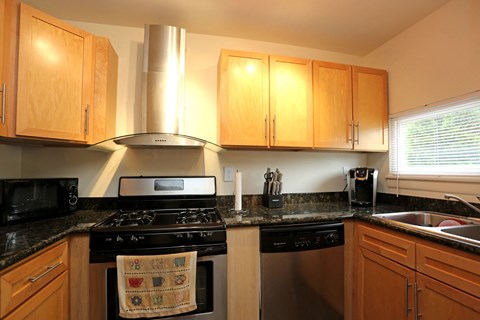 a kitchen with a stove and sink and wooden cabinets