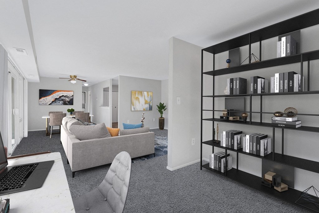 an open living room with a couch and a desk with a laptop