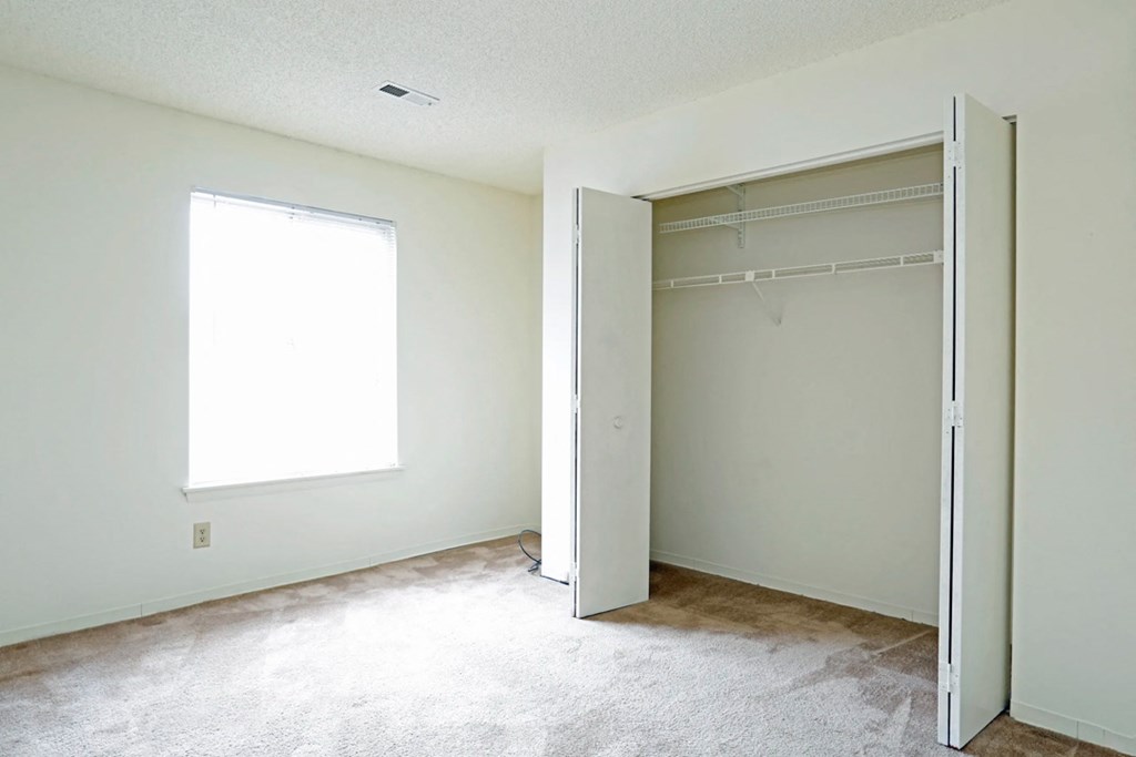 an empty room with a closet and a window