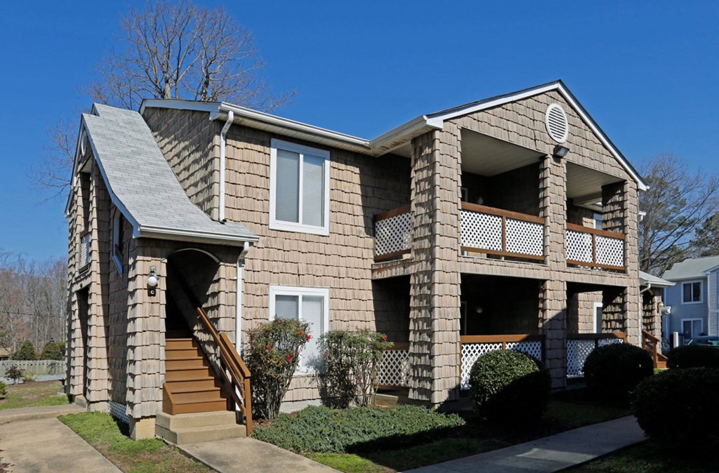 a tan brick house with a porch and stairs