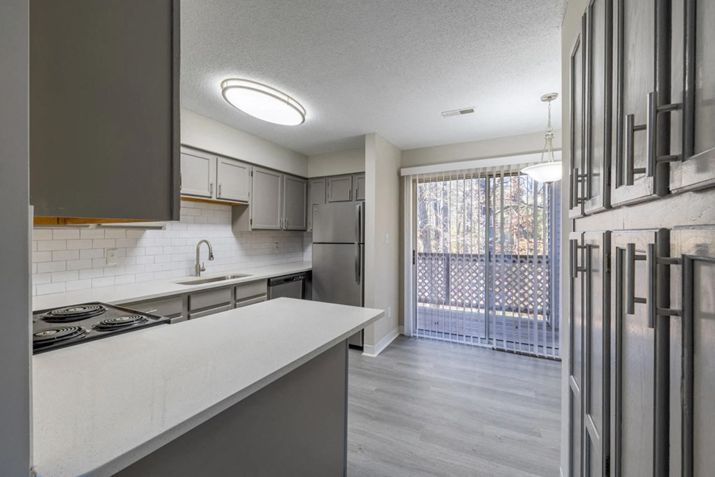 an empty kitchen with a sliding glass door to a balcony