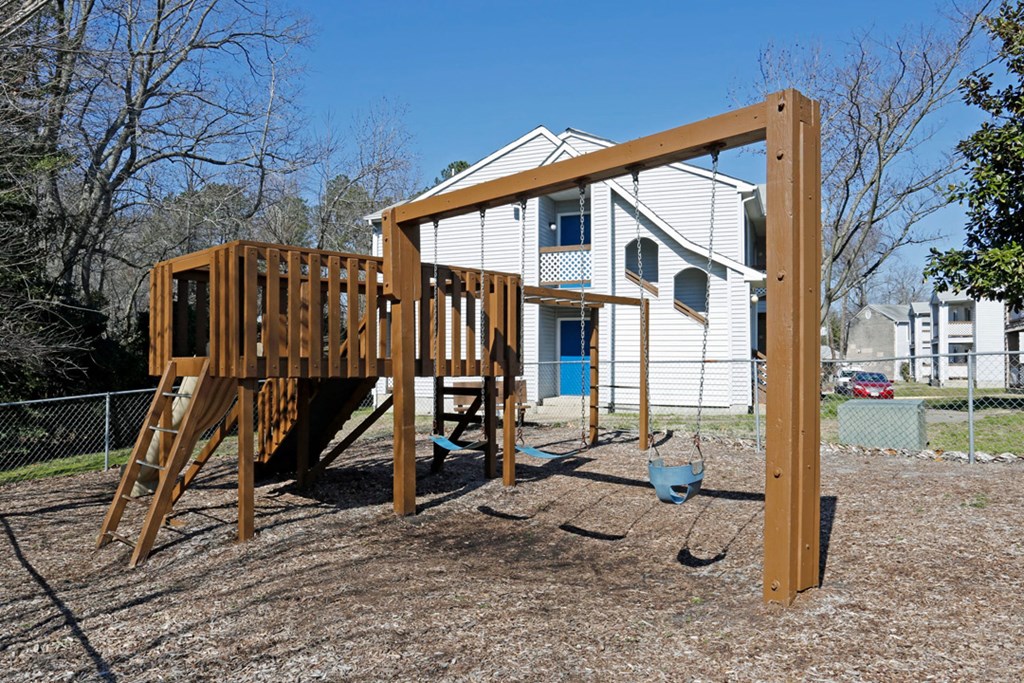 a playground with a swing set in front of a house