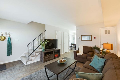 a living room with a couch and a tv in front of a staircase