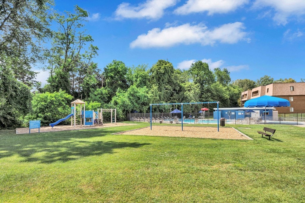 a grassy area with a playground and a building in the background