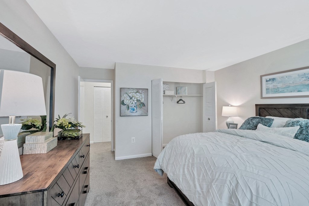 a bedroom with a large bed and a dresser with a mirror