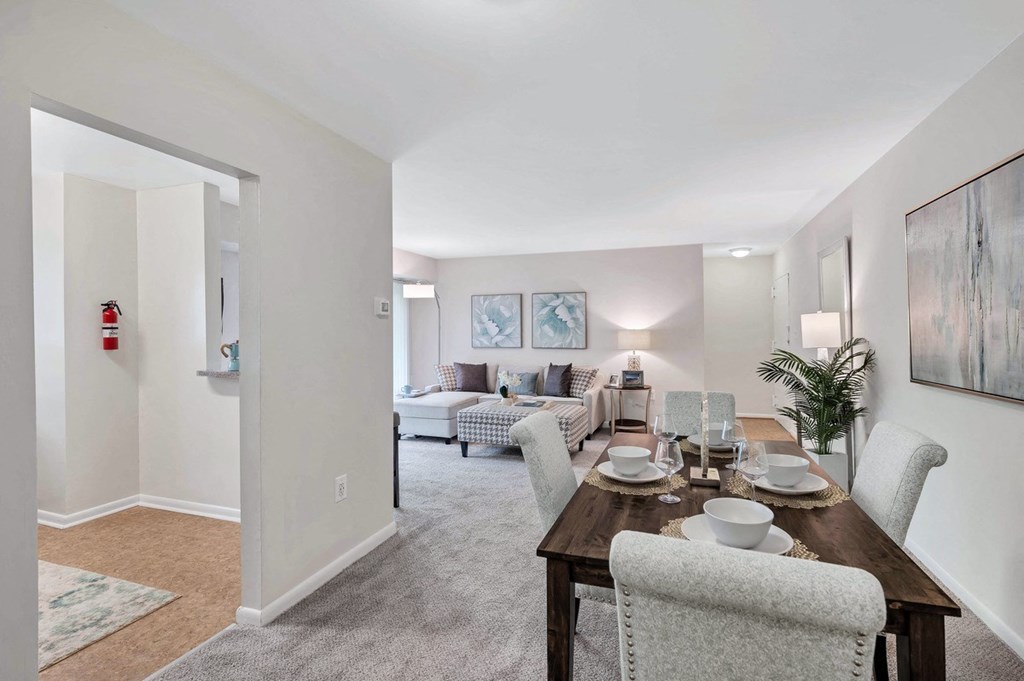 a dining room with a wooden table and chairs and a living room in the background