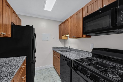 A kitchen with black appliances and wooden cabinets.