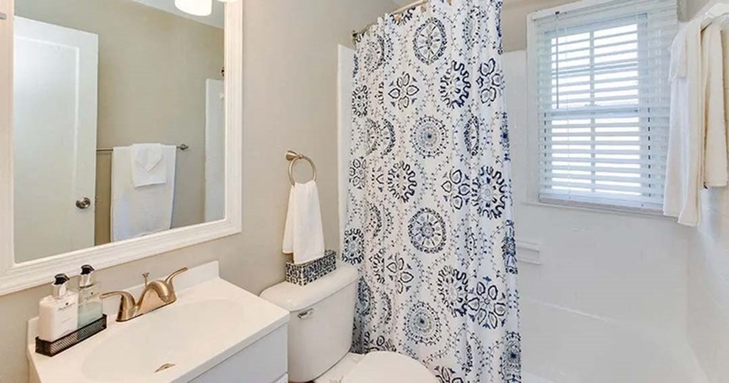 a bathroom with a white toilet and a sink and a shower curtain
