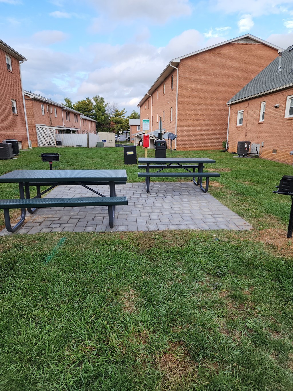 two picnic tables in a park in front of a building